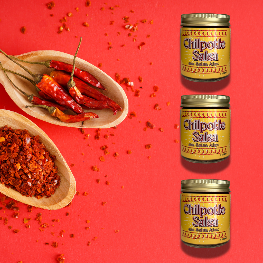 Three jars of Chipotle Salsa arranged vertically on a bright red background, with wooden bowls of dried red chilies and chili flakes scattered around. The labels read 'Chilpotle Salsa' and  'AKA Salsa Alex'.